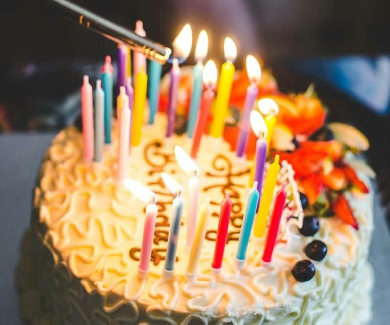 A birthday cake covered in lit candles