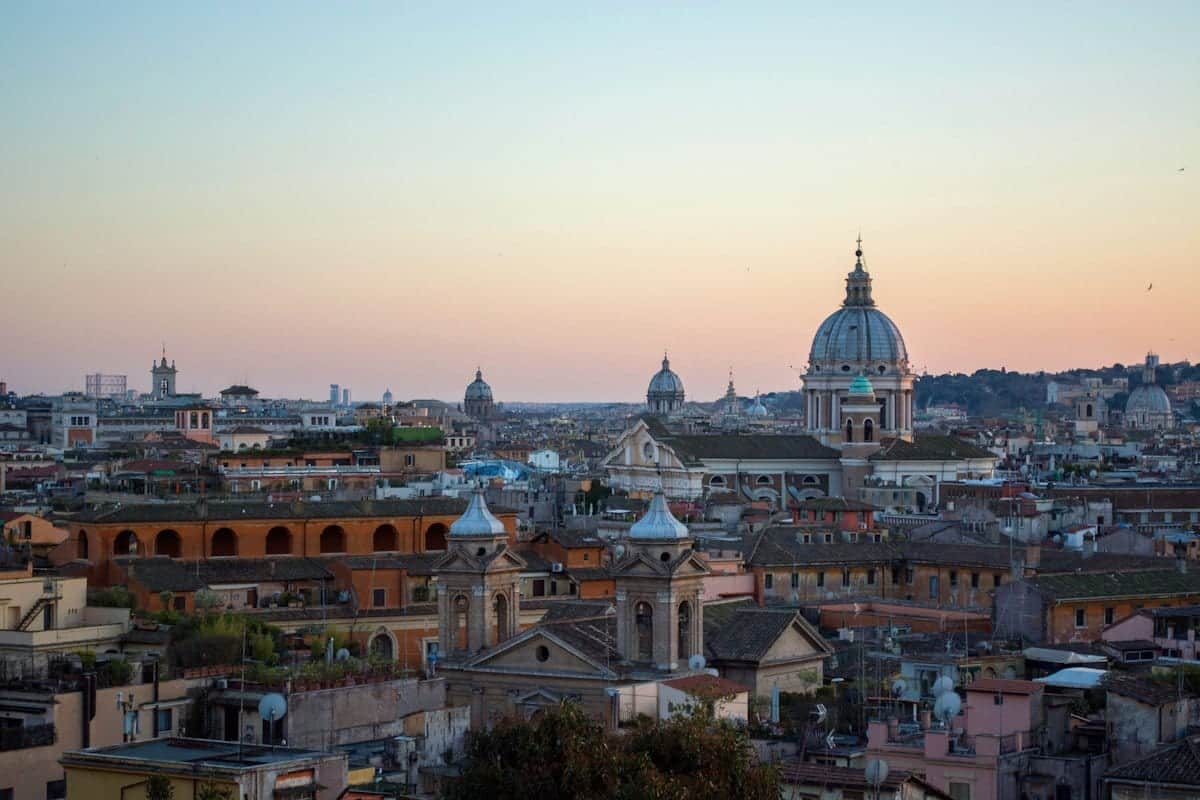 Rome's rooftops and church domes at dusk, thousands of homes side by side