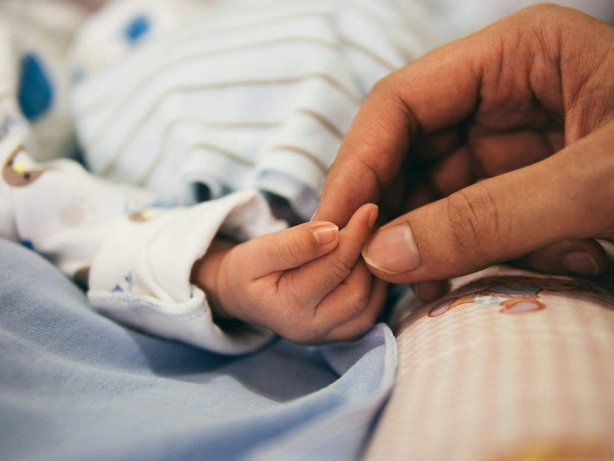 A baby's hand holding an adult's finger